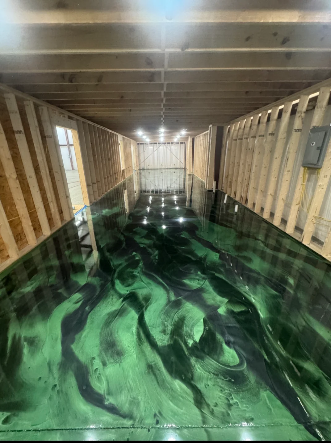 Metallic epoxy floor in deep emerald green with black marbling in a Murphy, NC warehouse